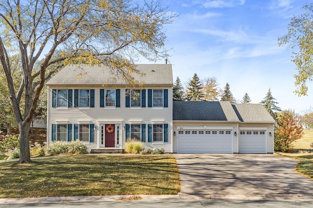 colonial inspired home featuring concrete driveway, a garage, and a front yard