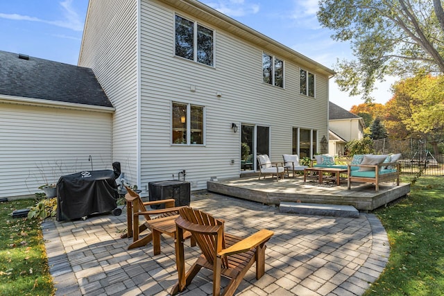 rear view of house featuring a deck, roof with shingles, a patio, and fence