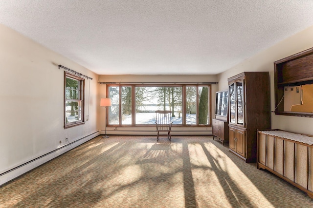 unfurnished room with a textured ceiling, baseboard heating, and carpet