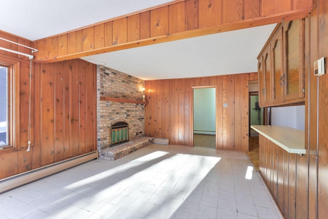 unfurnished living room featuring a brick fireplace, baseboard heating, and wood walls