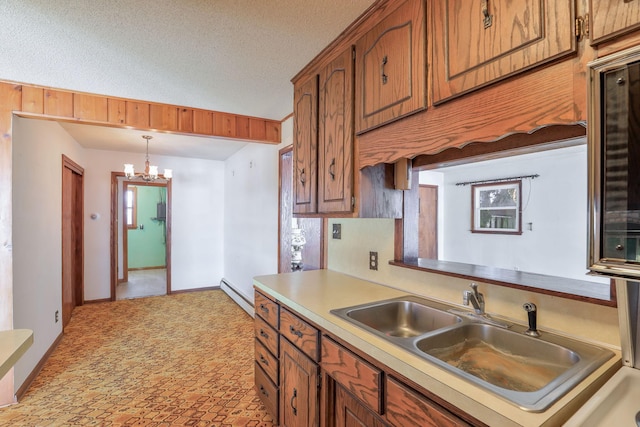 kitchen featuring a baseboard heating unit, a textured ceiling, a chandelier, pendant lighting, and sink