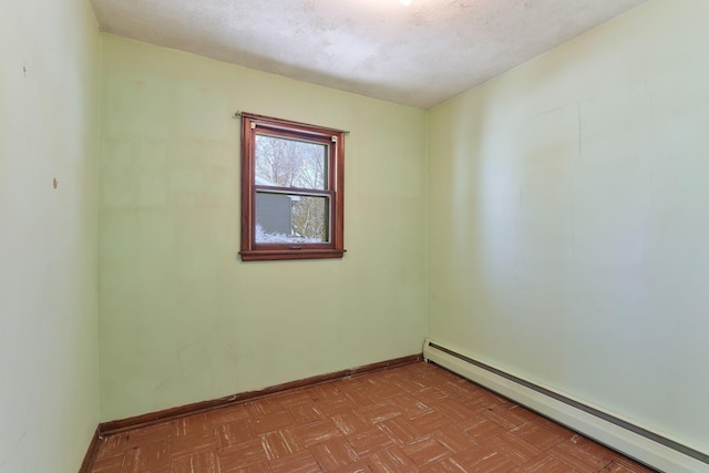 empty room featuring light parquet flooring, baseboard heating, and a textured ceiling