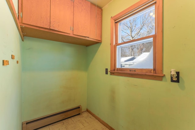 laundry area featuring a baseboard heating unit and cabinets