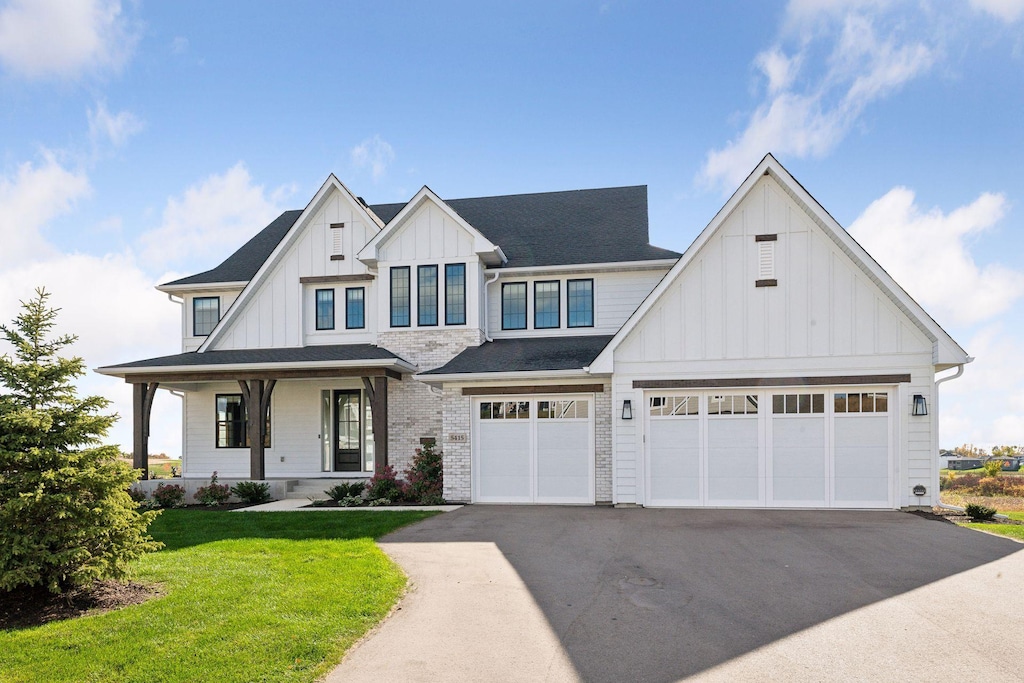 modern farmhouse featuring a front lawn, covered porch, and a garage