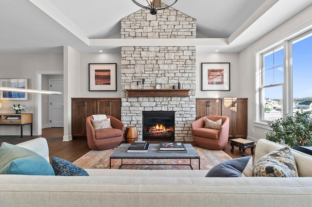 living room with baseboards, vaulted ceiling, wood finished floors, and a fireplace