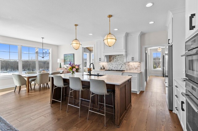 kitchen featuring decorative backsplash, a kitchen bar, a sink, light countertops, and white cabinets