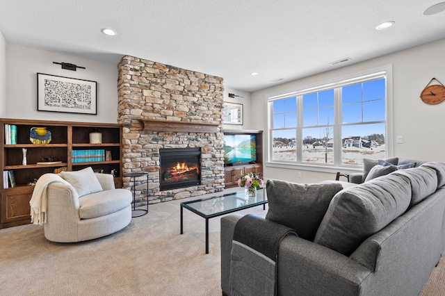 carpeted living room with a stone fireplace, recessed lighting, and visible vents