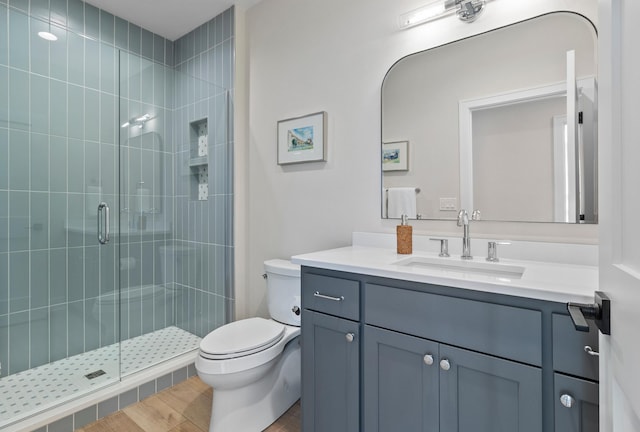 full bath featuring vanity, a stall shower, toilet, and wood finished floors
