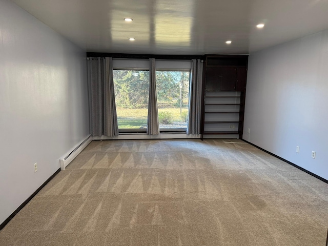 carpeted spare room featuring a baseboard heating unit