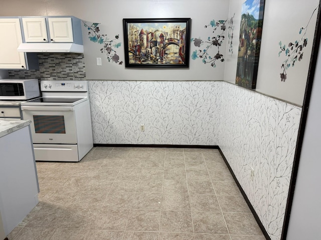 kitchen with white cabinets, light tile patterned floors, and white appliances