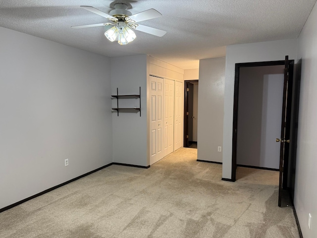 unfurnished bedroom featuring a textured ceiling, light colored carpet, and ceiling fan