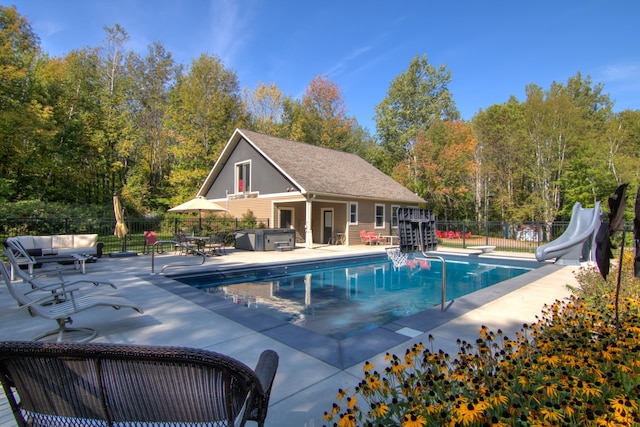 view of swimming pool with a patio, a water slide, and an outbuilding