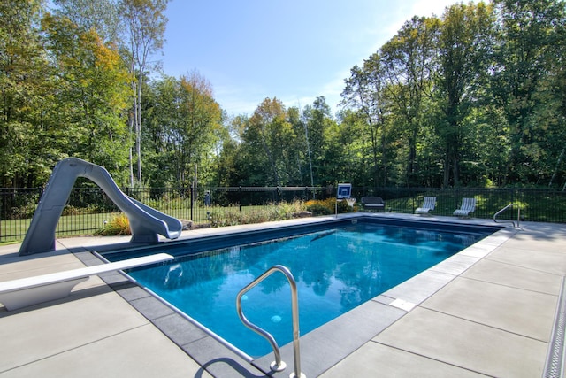 view of pool featuring a patio, a water slide, and a diving board