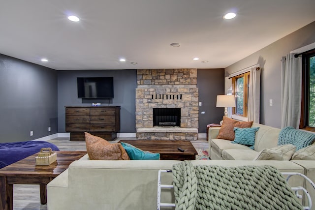 living room with light wood-type flooring and a stone fireplace