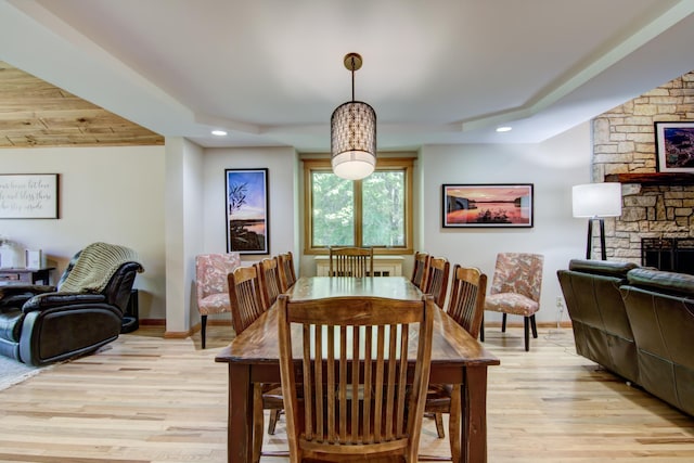 dining area featuring light wood-type flooring and a stone fireplace