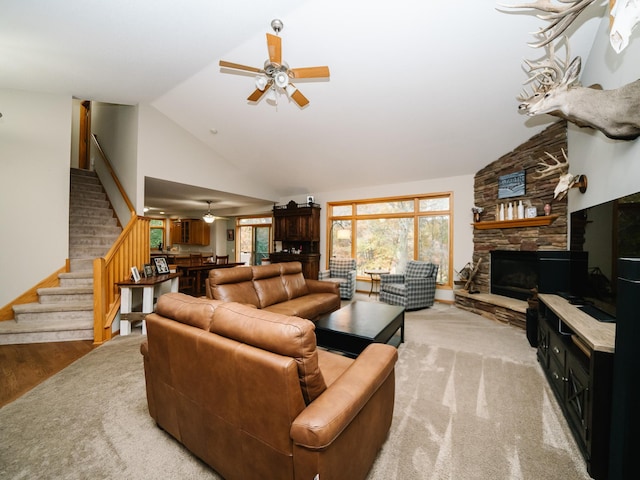 living room featuring a stone fireplace, high vaulted ceiling, light wood-type flooring, and ceiling fan