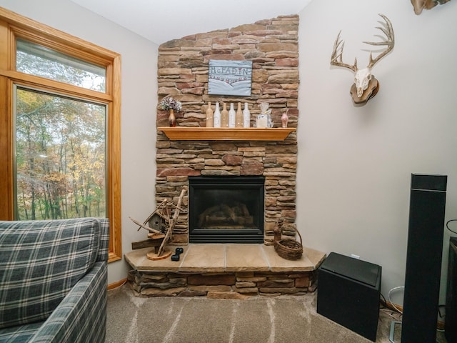 living room with a stone fireplace, carpet floors, and vaulted ceiling