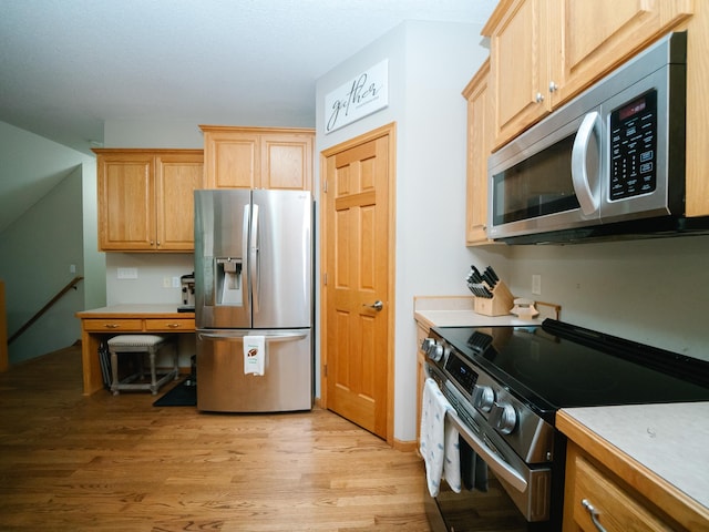 kitchen featuring light brown cabinetry, stainless steel appliances, and light hardwood / wood-style floors