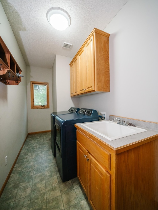 laundry area featuring cabinets, a textured ceiling, sink, and washing machine and dryer