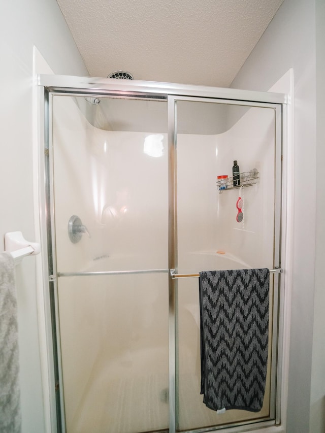 bathroom with a shower with shower door and a textured ceiling