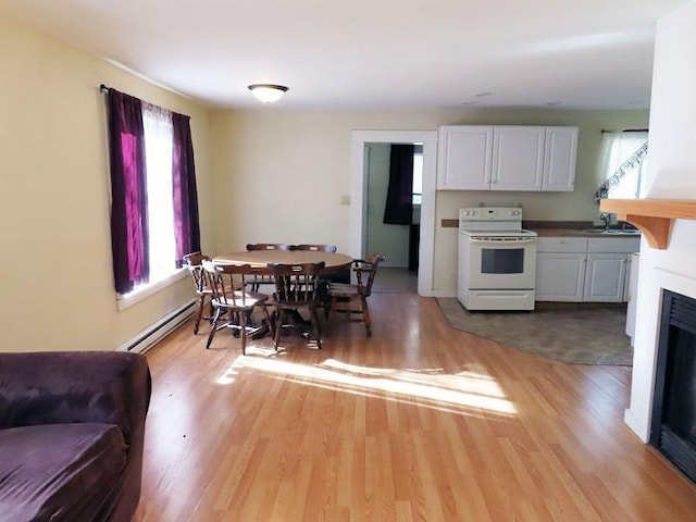 kitchen featuring a baseboard heating unit, white range with electric cooktop, light wood-type flooring, and white cabinetry