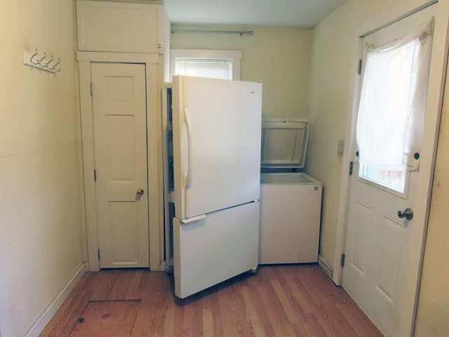 kitchen featuring white refrigerator, light wood-type flooring, and a healthy amount of sunlight