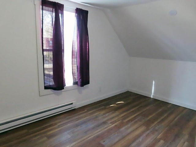 additional living space with vaulted ceiling, a baseboard heating unit, and dark hardwood / wood-style flooring