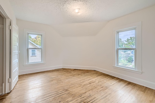 bonus room featuring lofted ceiling, light hardwood / wood-style flooring, and a textured ceiling