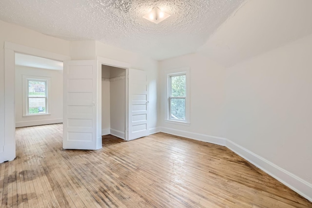 unfurnished bedroom with multiple windows, a closet, and hardwood / wood-style floors