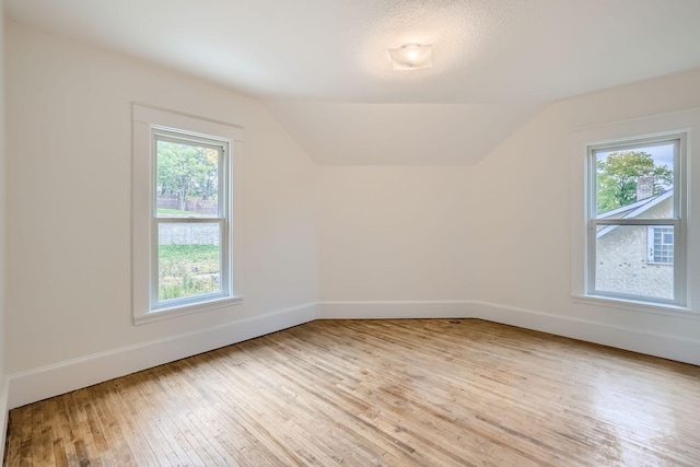 bonus room with lofted ceiling, light hardwood / wood-style floors, and a wealth of natural light