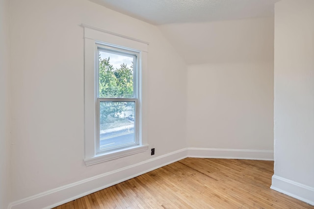 bonus room with a textured ceiling, lofted ceiling, and light wood-type flooring