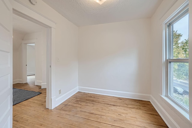 spare room featuring light wood-type flooring and a textured ceiling