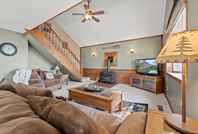 living room featuring a wealth of natural light, wooden walls, carpet flooring, and a wood stove