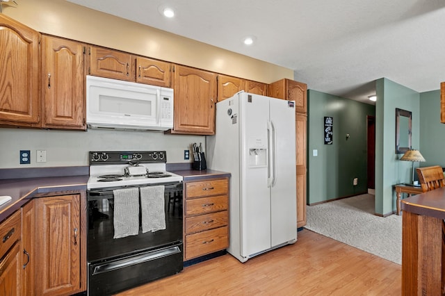 kitchen with white appliances and light hardwood / wood-style flooring