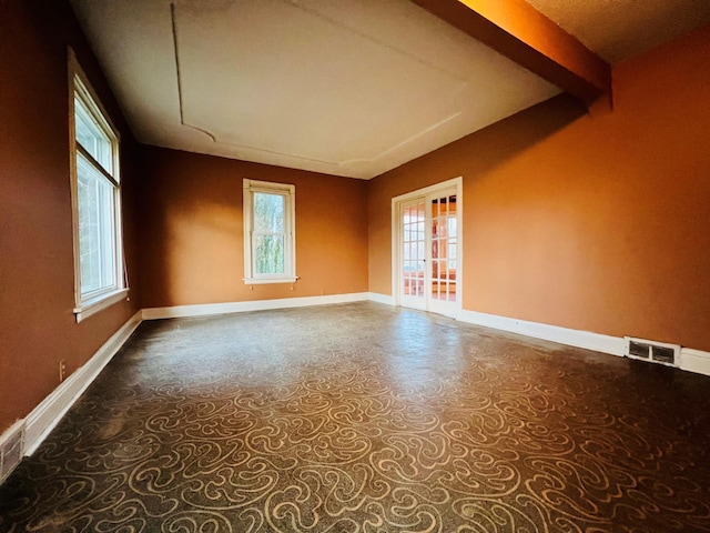 empty room featuring beam ceiling and a wealth of natural light