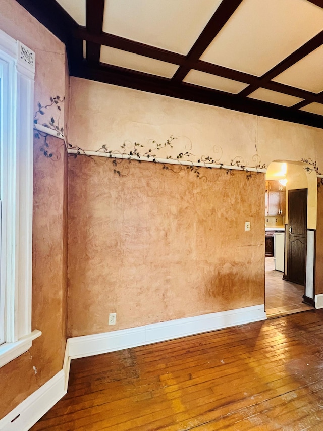 unfurnished room with beam ceiling, coffered ceiling, and hardwood / wood-style flooring