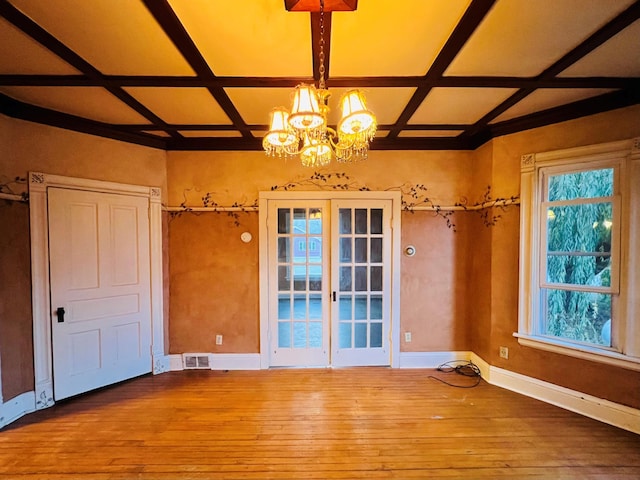 spare room with beamed ceiling, coffered ceiling, hardwood / wood-style flooring, and a chandelier