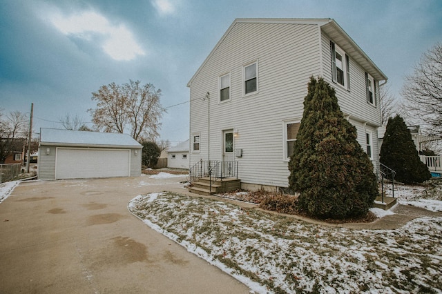 view of snow covered exterior featuring a garage and an outbuilding