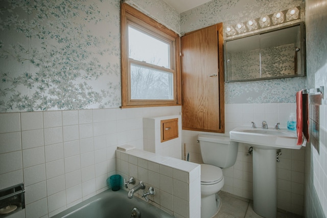 bathroom with tile patterned flooring, toilet, tile walls, and a tub