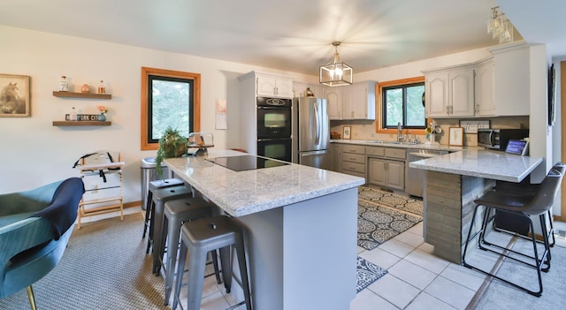 kitchen featuring a breakfast bar area, black appliances, a peninsula, and a sink