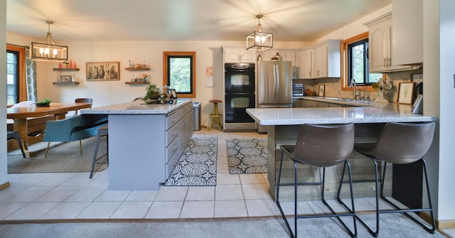 kitchen featuring a sink, dobule oven black, a breakfast bar, a peninsula, and freestanding refrigerator