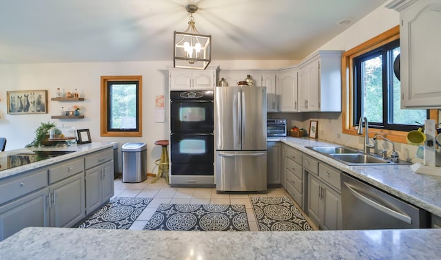 kitchen with black appliances, light tile patterned floors, gray cabinets, and a sink