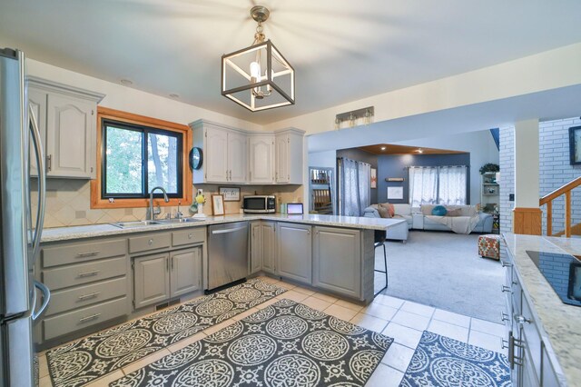 kitchen featuring a sink, stainless steel appliances, light tile patterned flooring, gray cabinets, and light colored carpet