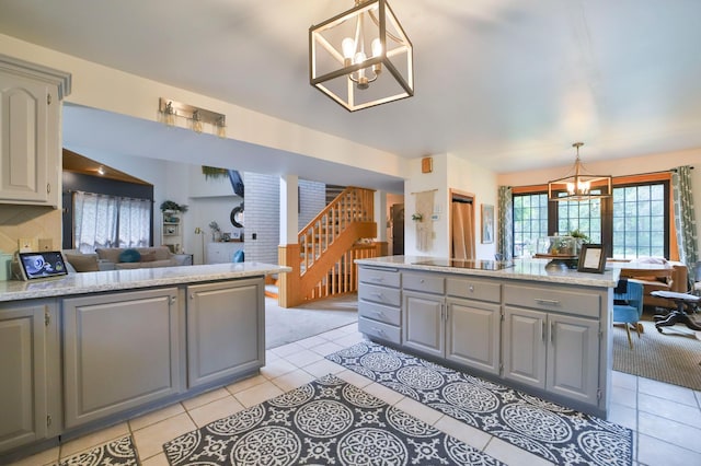 kitchen featuring light tile patterned flooring, a notable chandelier, a peninsula, pendant lighting, and gray cabinetry
