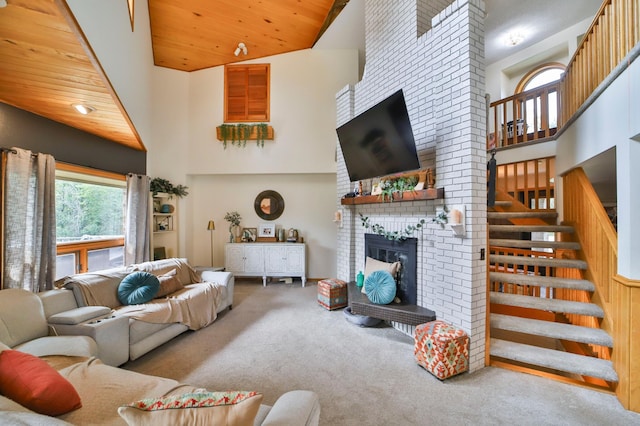 carpeted living room featuring stairway, a high ceiling, a fireplace, and wooden ceiling