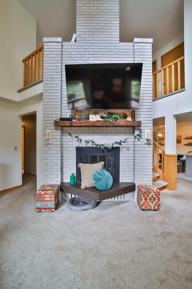carpeted living area featuring a fireplace and a high ceiling