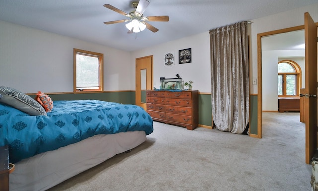 carpeted bedroom with a ceiling fan and multiple windows