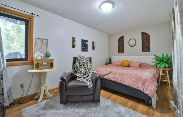 bedroom with a textured ceiling, wood finished floors, and baseboards