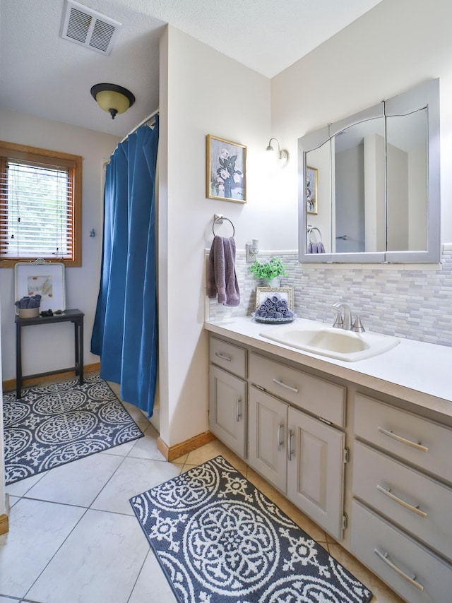bathroom featuring tile patterned flooring, visible vents, vanity, and tasteful backsplash