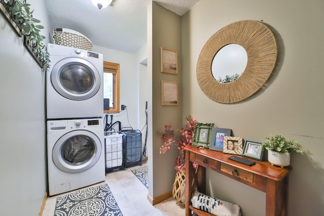 laundry room featuring light tile patterned floors, laundry area, baseboards, stacked washer / dryer, and a textured ceiling